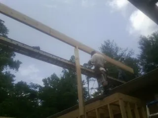 Carpenter setting a ridge beam over a new addition frame — Ice Dam Removal by Roofing Brothers in Lutts