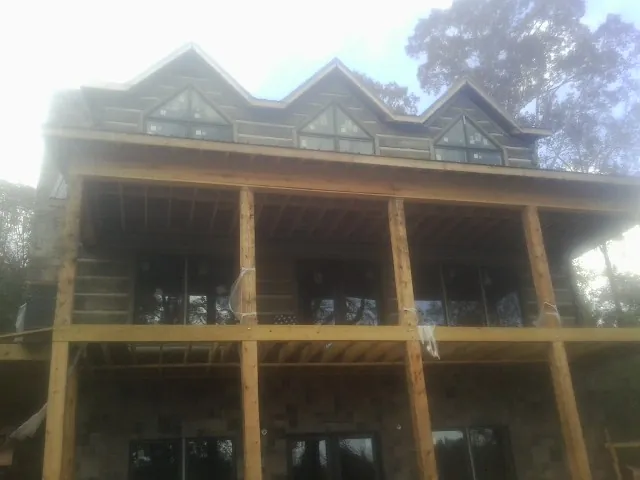Dormers and porch framing on a large log home under construction — Roof Coating work by our crew in Lutts