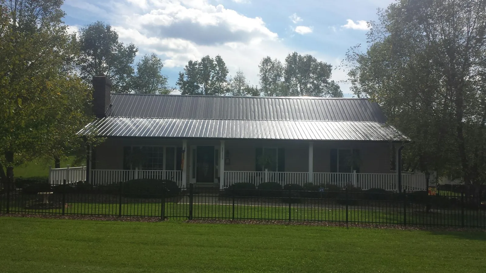 Gray metal roof on a brick ranch with a full width front porch — Gutter Guard Installation work by our crew in Lutts