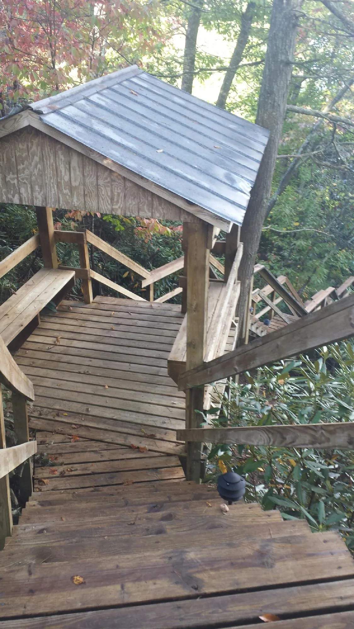 Metal roofed shelter over wooden steps on a wooded walkway — Skylight Repair & Installation work by our crew in Lutts