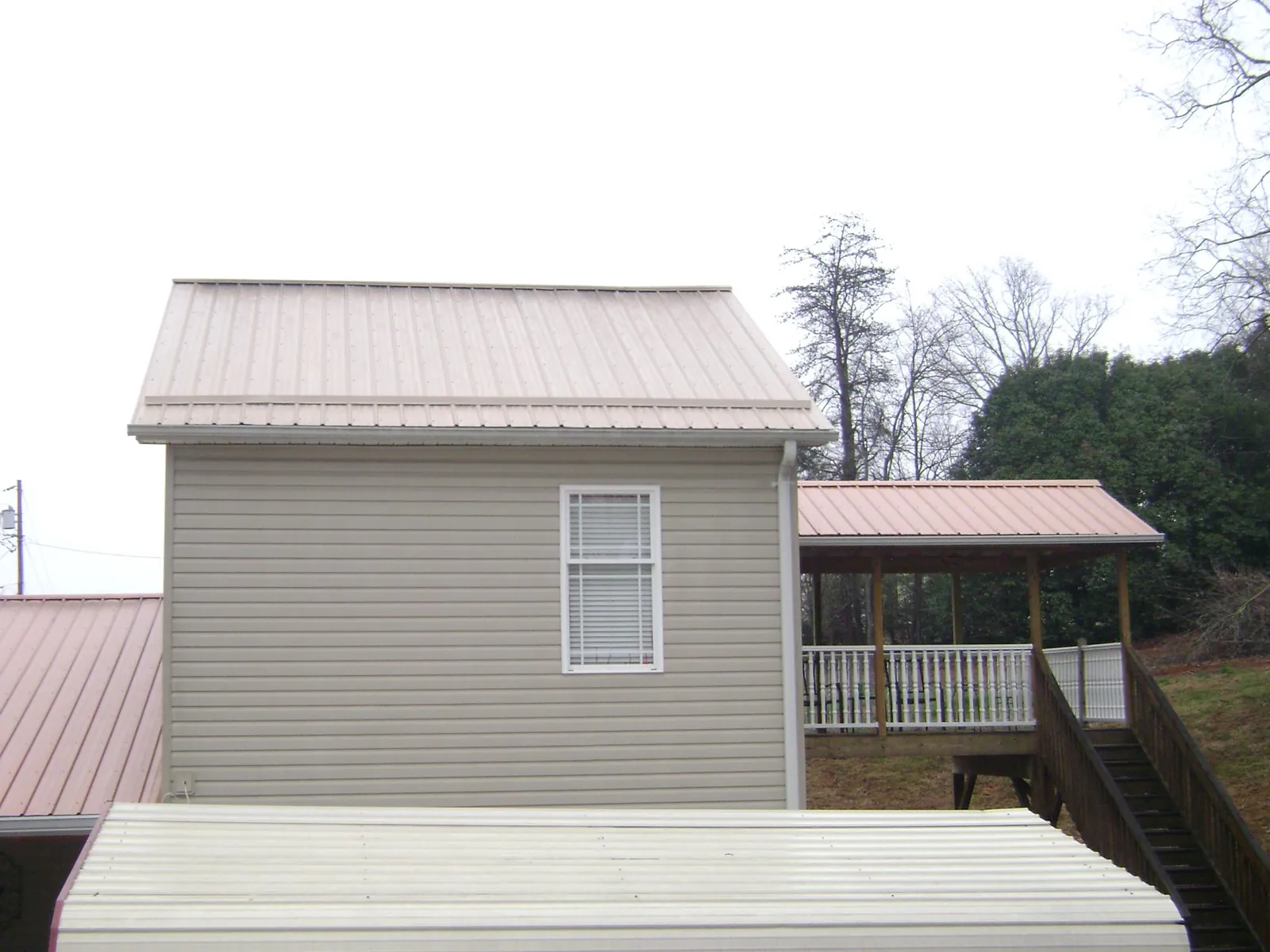 Tan metal roofs on a two story addition and attached porch, from a Roof Replacement job in Lutts