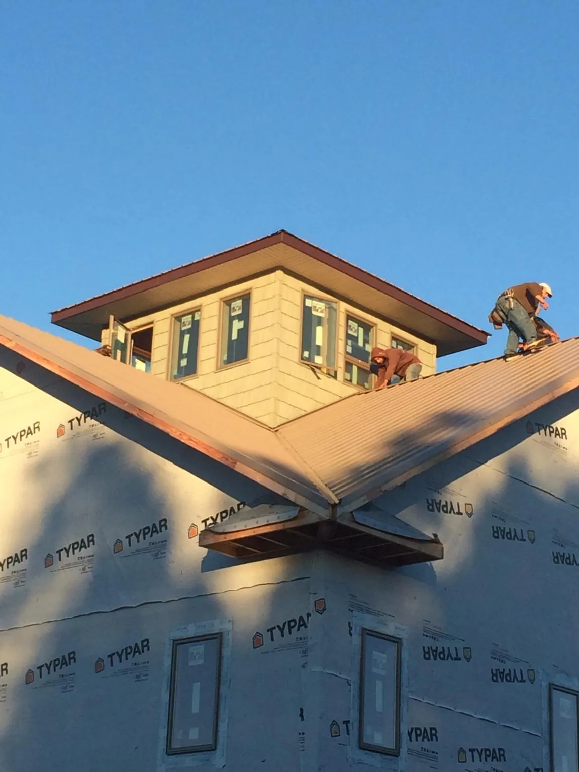 Roofers working around a rooftop cupola on a new metal roof at sunset — Roof Waterproofing in Lutts by Roofing Brothers